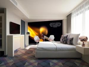 a bedroom with a bed with two chairs and a tv at Science Hotel Prémium in Szeged