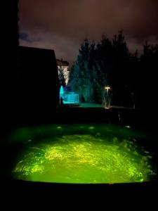 una piscina de luz verde en un patio por la noche en U Yaroslava Hotel, en Yaremche