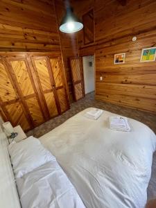 Cama grande en habitación con paredes de madera en Cabaña La Elisa en Villa La Angostura