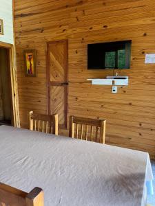 a bedroom with a bed and two chairs and a television at Cabaña La Elisa in Villa La Angostura