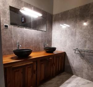 - une salle de bains avec deux lavabos sur un comptoir en bois dans l'établissement Chez Nous Chez Vous, à Toubakouta