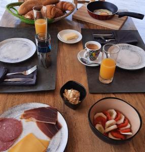 a table topped with plates of breakfast foods and orange juice at Chez Nous Chez Vous in Toubakouta