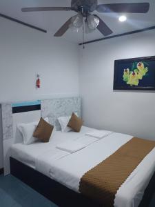 um quarto com uma cama branca e uma ventoinha de tecto em Kotchaphorn Garden em South Pattaya