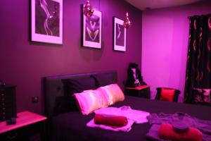 a purple room with a bed with pink sheets and pillows at SECRET33 in Floirac