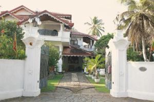 een wit huis met een poort en palmbomen bij Preethi Village in Negombo
