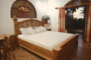 a bedroom with a large wooden bed with white sheets at Preethi Village in Negombo