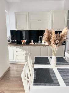 a white kitchen with a table with a vase with flowers at Central Residence in Baia Mare