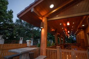 una terraza de madera con un banco y una mesa en HUAN CHOM JAN Hometel at Lampang 