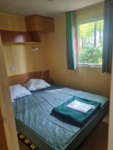 um pequeno quarto com uma cama e uma janela em PUY du FOU 5P H004 em La Boissière-de-Montaigu