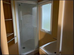 uma casa de banho com um chuveiro, uma banheira e uma janela. em PUY du FOU 5P H004 em La Boissière-de-Montaigu