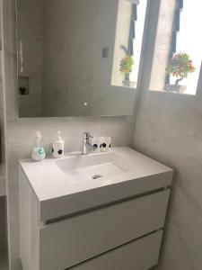 a white bathroom with a sink and a mirror at Quinta Shiamar in Quarteira