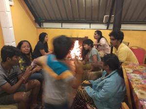 Un groupe de gens assis autour d'un feu dans l'établissement Blossomwell Bungalow, à Nuwara Eliya