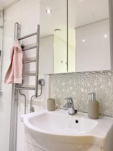 ein weißes Badezimmer mit Waschbecken und Spiegel in der Unterkunft Tilava kaksio- Keskusta- Autopaikka in Rovaniemi