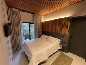 1 Schlafzimmer mit einem weißen Bett und einem Balkon in der Unterkunft Pousada Encontro das Águas in Gonçalves