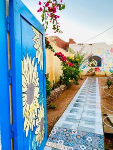una porta blu con un dipinto di un girasole sopra di Blue House in Lighthouse a Dahab