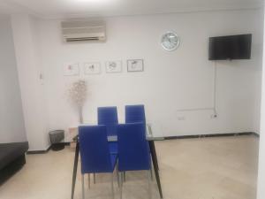 a table with blue chairs in a room with a clock at Mérida Monumental y Vacacional in Merida
