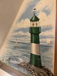 a painting of a lighthouse with a boat in the water at Ferienwohnung LoWu in Hagen