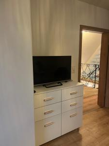 eine weiße Kommode mit einem Fernseher darüber in der Unterkunft Ferienwohnung LoWu in Hagen