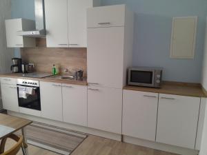 a kitchen with white cabinets and a microwave at Ferienwohnung Mantei in Altentreptow