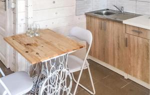 - une cuisine avec une table en bois et des chaises blanches dans l'établissement Gorgeous Home In Rybical With Kitchen, à Ryn