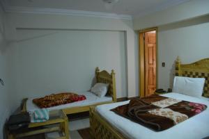 1 Schlafzimmer mit 2 Betten, einem Fenster und einer Tür in der Unterkunft PC Green Hotel, Mahandri, Kaghan in Mingora