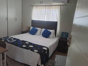 Un dormitorio con una cama con almohadas azules y una ventana en Virgin guesthouse en Francistown