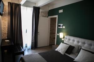 ein Schlafzimmer mit einer grünen Wand, einem Bett und einem Fenster in der Unterkunft B&B Agorà in Bitetto