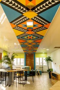 a lobby with a colorful ceiling with tables and chairs at People Hostel & Coworking in Bishkek