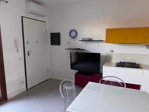 uma cozinha com uma televisão e uma mesa e cadeiras em Casa di Sveva em Marotta