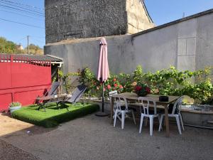 un patio con mesa, sillas y sombrilla en la cave en Montoire-sur-le-Loir