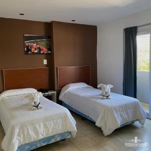 um quarto com 2 camas e lençóis brancos em Hotel internacional em Termas de Río Hondo