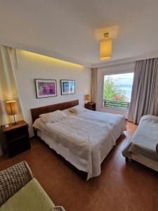 een slaapkamer met 2 bedden en een groot raam bij Casa Surucuá com localização espetacular frente à Praia do Centro de Pipa - 2 a 4 quartos suite in Pipa