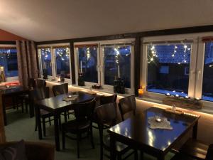 un restaurante con mesas y sillas y ventanas con luces de Navidad en Pension Mühlhahn, en Schierke
