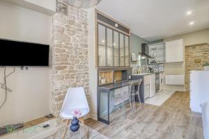 een woonkamer met een stenen muur en een tv bij Comfortable fully equipped studio - City Center in Dijon