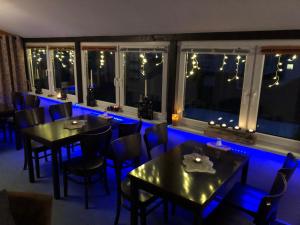 a restaurant with tables and chairs and blue lighting at Pension Mühlhahn in Schierke