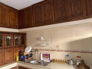 a kitchen with wooden cabinets and a counter top at Appartement meublé sans vis à vis proche de toutes commodités 5 min à Marjane chaikh Zaid et centre ville in Khouribga