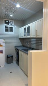 a kitchen with white cabinets and a sink and a refrigerator at شقق ثمانين بارك 2 in Khamis Mushayt