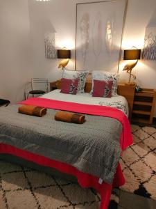 Schlafzimmer mit einem Bett mit roter und grauer Bettwäsche und Kissen in der Unterkunft La suite 27, chambre d'hôtes de charme in Guingamp