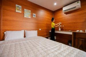 uma mulher num quarto de hotel com uma cama em Homestay Mường Trời em Dien Bien Phu