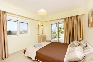een slaapkamer met een groot bed en ramen bij Elli Garden View - Spacious Fully Equipped Apartment in Kremasti
