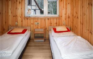 two beds in a wooden room with a window at Lovely Home In Wilimy With House A Panoramic View in Dadaj