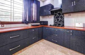 a kitchen with black cabinets and a red counter top at Abbey Cottage in Dharamshala