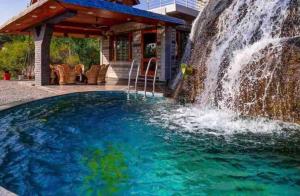 a waterfall next to a swimming pool with a waterfall at Abbey Cottage in Dharamshala