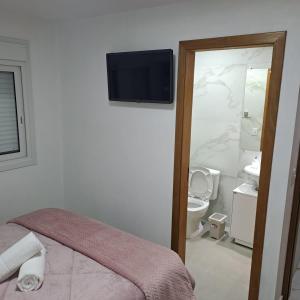 a bathroom with a toilet and a television on the wall at Casa Missões Dill Haus 1 in Gramado