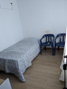 a bedroom with two blue chairs and a bed at Charming Village, Tiny House in Santa Marta