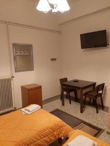 a room with a bed and a table and a television at Ermis Hotel 