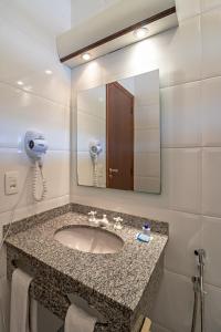 uma casa de banho com um lavatório e um espelho em Pousada do Lago em Brotas