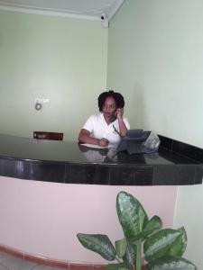 SEED HOTEL في عنتيبي: امرأة تجلس في مكتب مع جهاز كمبيوتر محمول