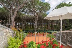 a fence with an umbrella and some flowers at Condominio Dunelba in Marina di Campo