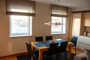 a dining room with a table and chairs and two windows at Vilmsi 44 cozy 85m2 apartment with sauna in Kadriorg in Tallinn